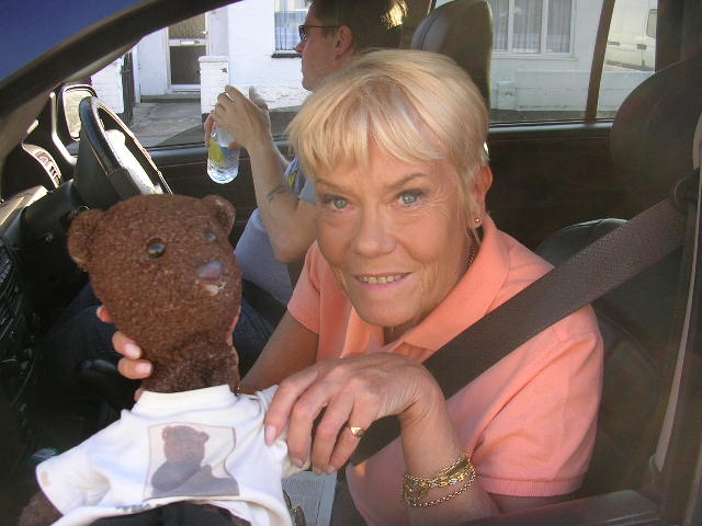 Wendy Richard holding Bearsac in window of car.