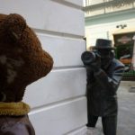 Paparazzi statue peering around corner with camera stalking Bearsac
