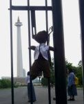Bearsac hanging by his straps on a fence poiting at the Jakarta National Monument