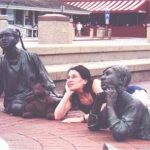 Debra and Bearsac sitting with brass children at foot of the Alex Haley monument