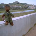 Bearsac sitting on a wall with River Besòs and urban mountain scenery