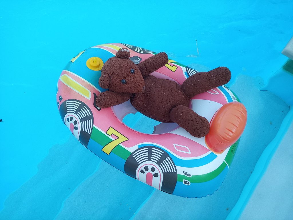 Bearsac naked floating on the pool in an inflatable toy boat