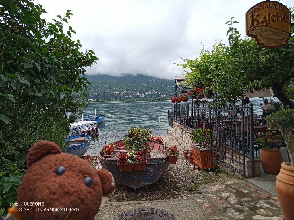Bearsac in forgrouund of lake, restaurant and cloud covered moutain scene