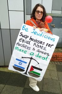 Woman and teddy bear with poster reading - Be Jewdicious, Swap hostages for equal rights, facilities and services. Make a deal.