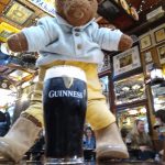 Bearsac the teddy bear sitting on a table with a pint of GUinniss