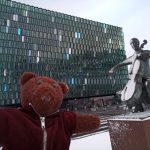 Bearsac the teddy bear beside the Musician monument in foreground of Harpa Concert Hall