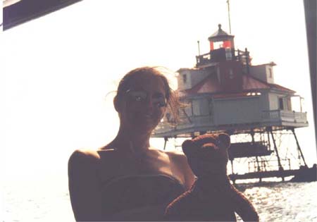 Debra holding Bearsac in front of Thomas Moore Lighthouse, which is on stilts in the water.