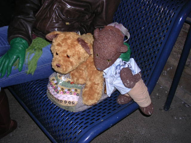 Bearsac and a teddy bear on a bag on public seat