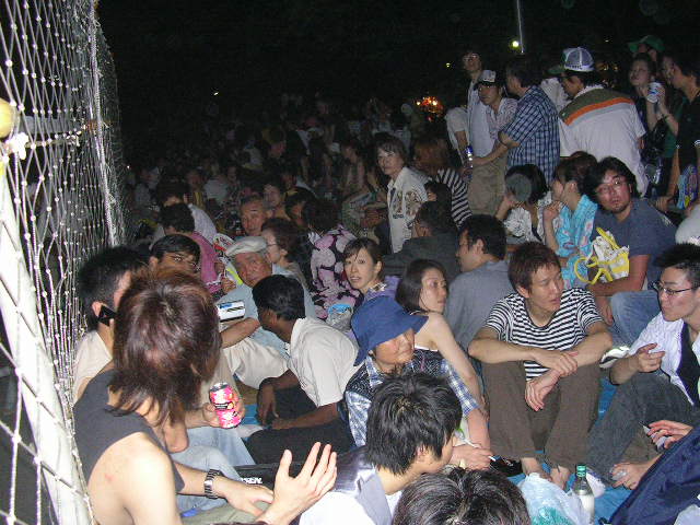 People sitting on ground waiting for fireworks.