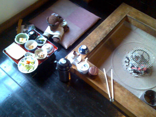 Bearsac on floor cushion in front of food.