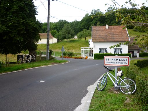 Bearsac on bicycle prompt up against place sign for Offanville