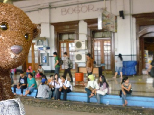 Bearsac at Bogor railway station with people sitting with the feet on the nearest track.