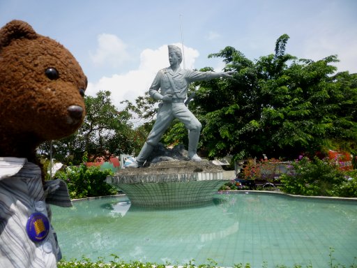 Bearsac beside a statue of a pointing soilder.
