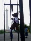 Bearsac hanging by his straps on a fence poiting at the Jakarta National Monument