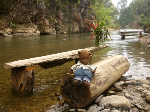 Bearsac sitting on a log bench at a log table in a very shallow part of the shallow Soppong River