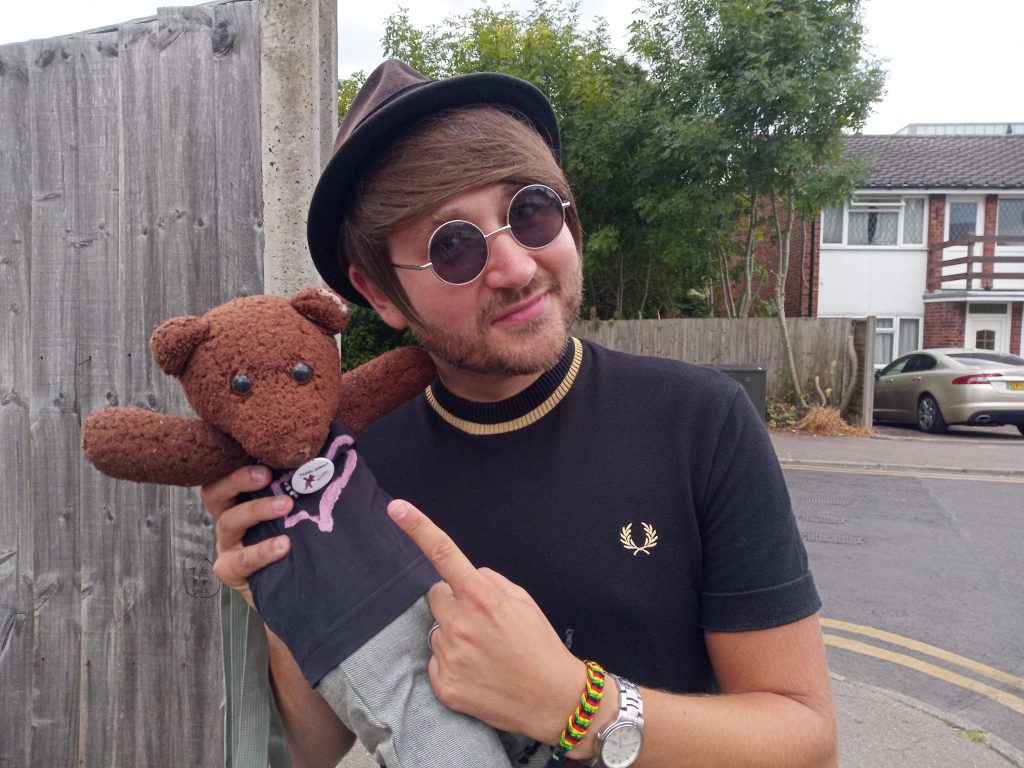 Ben Champniss holding and pointing to teddy bear, Bearsac