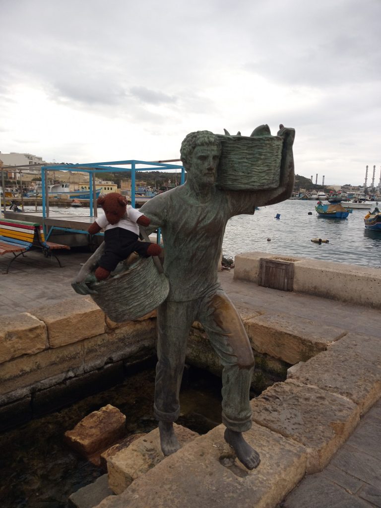 Bearsc in basket of sculpture of fisherman