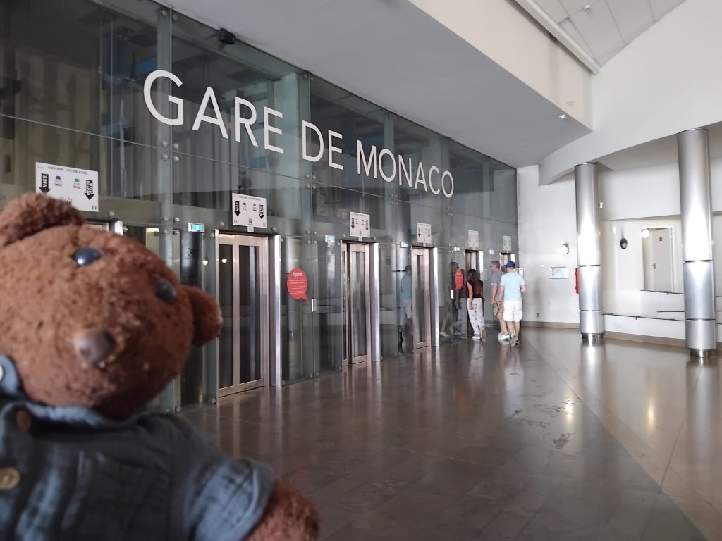 Teddy bear Bearsac in the foreground of train station lifts