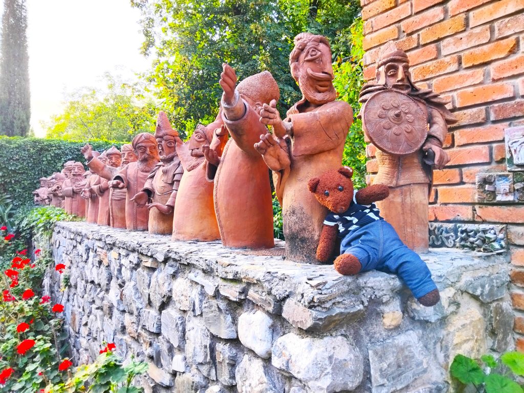 Bearsac the teddy bear in forground of teracotta modles of people.