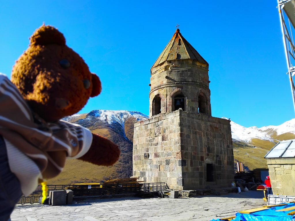 Bearsac the teddy bear in forground of Gergeti Trinity Church