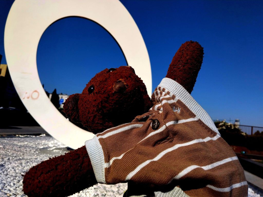 Bearsac the teddy bear with the letter O in a monument looking like a halo.