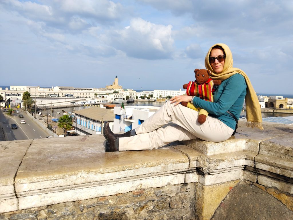 Bearsac the teddy bear iand his mummy sitting ona wall in forground of a harbour view.