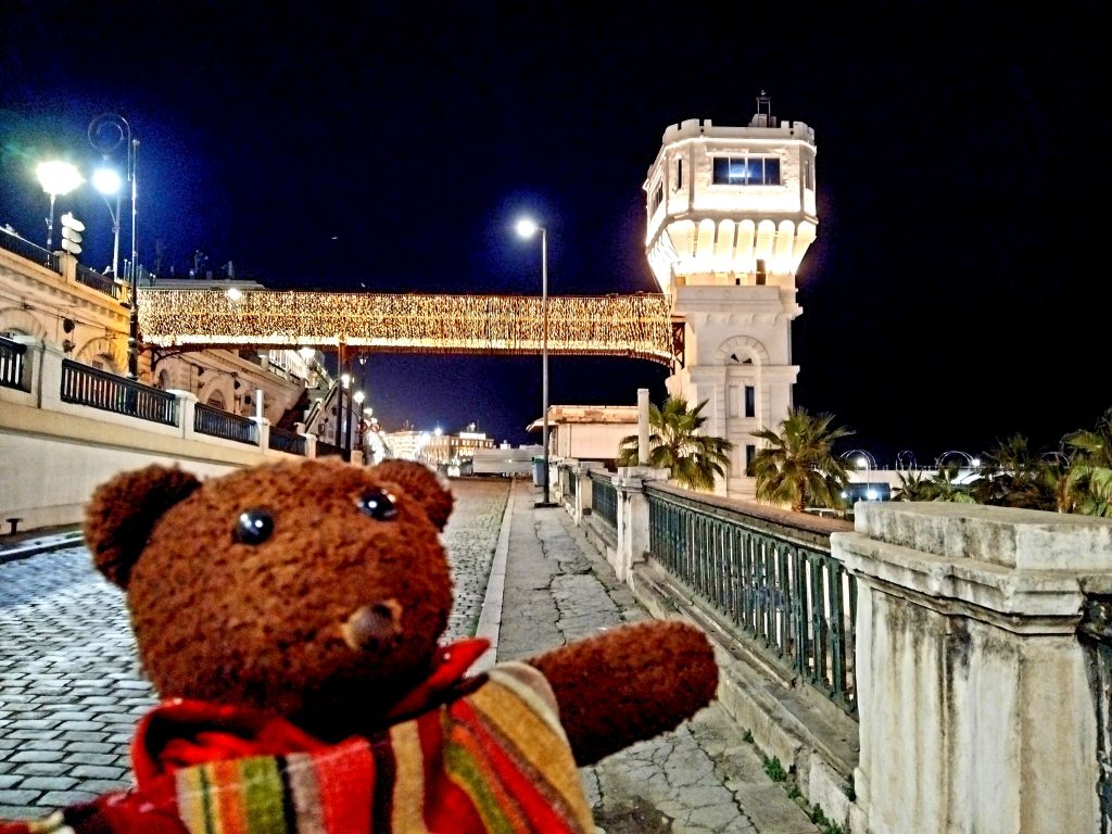 Bearsac the teddy bear in forground of a bridge at night
