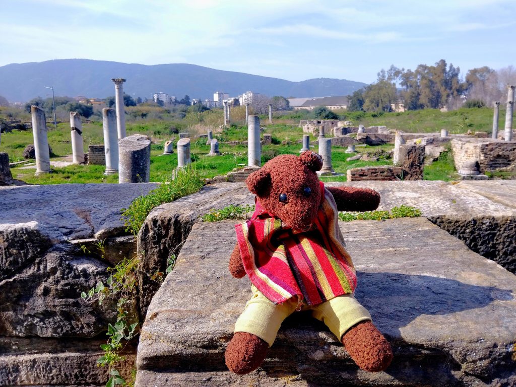 Bearsac the teddy bear in forground of ruins