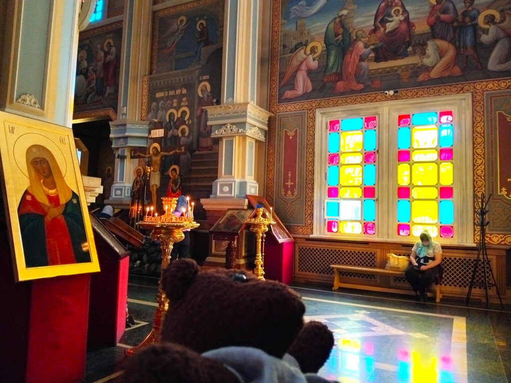 Bearsac the teddy bear in the forerground of stained glass windows