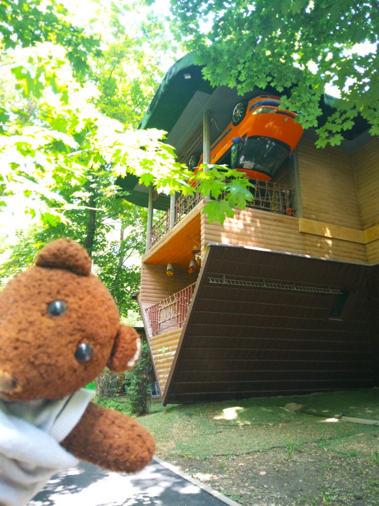 Bearsac the teddy bear in the forerground of the upisde down house