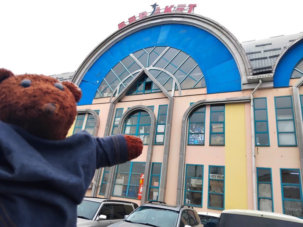 Bearsac the teddy bear in the forerground of a building