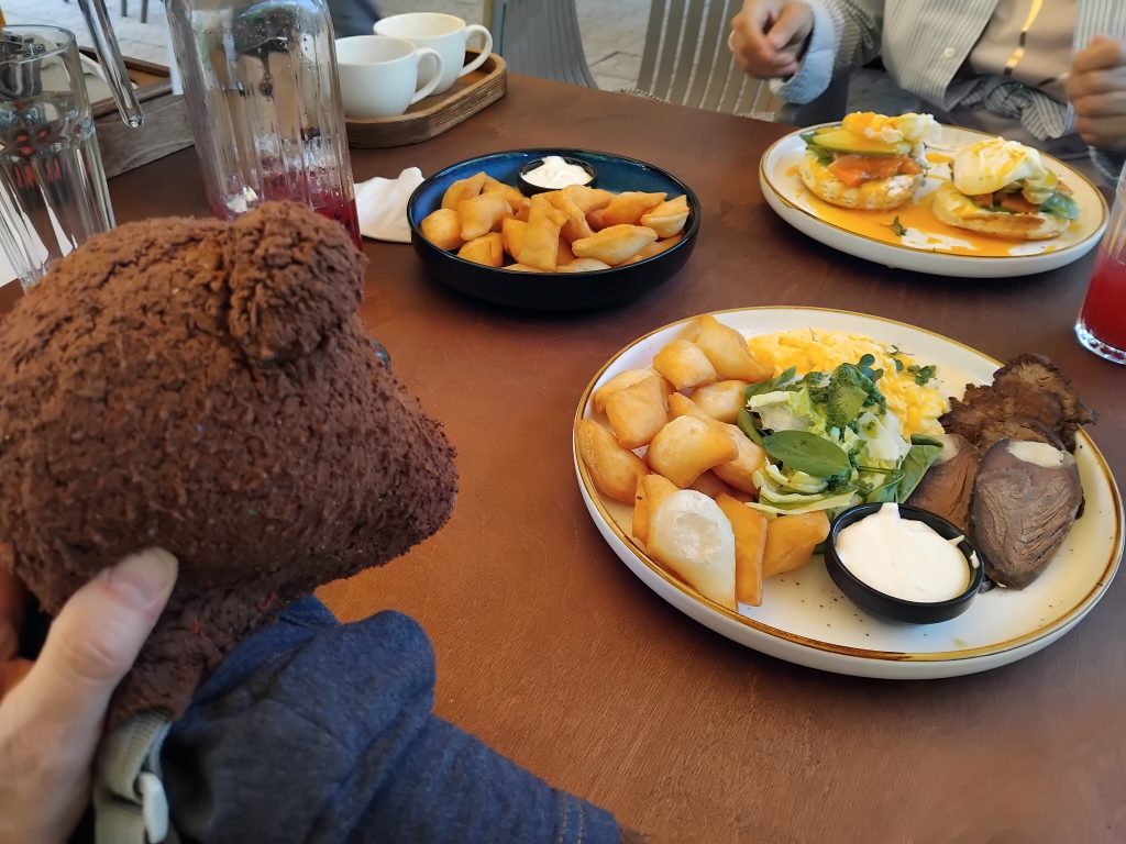 Bearsac the teddy bear in the forerground of atale with food