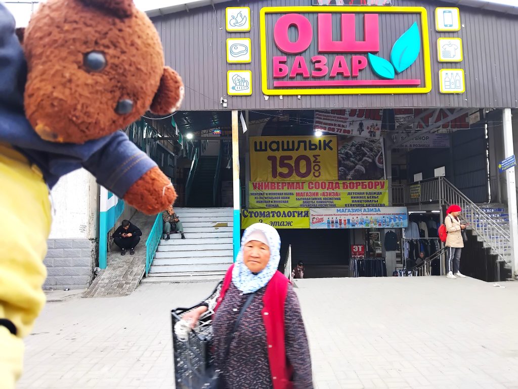 Bearsac the teddy bear in the forerground of Osh Market