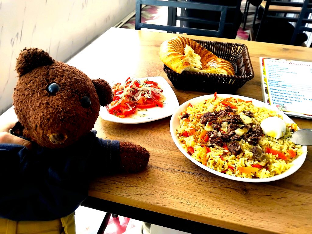 Bearsac the teddy bear in the forerground of a plate of plov