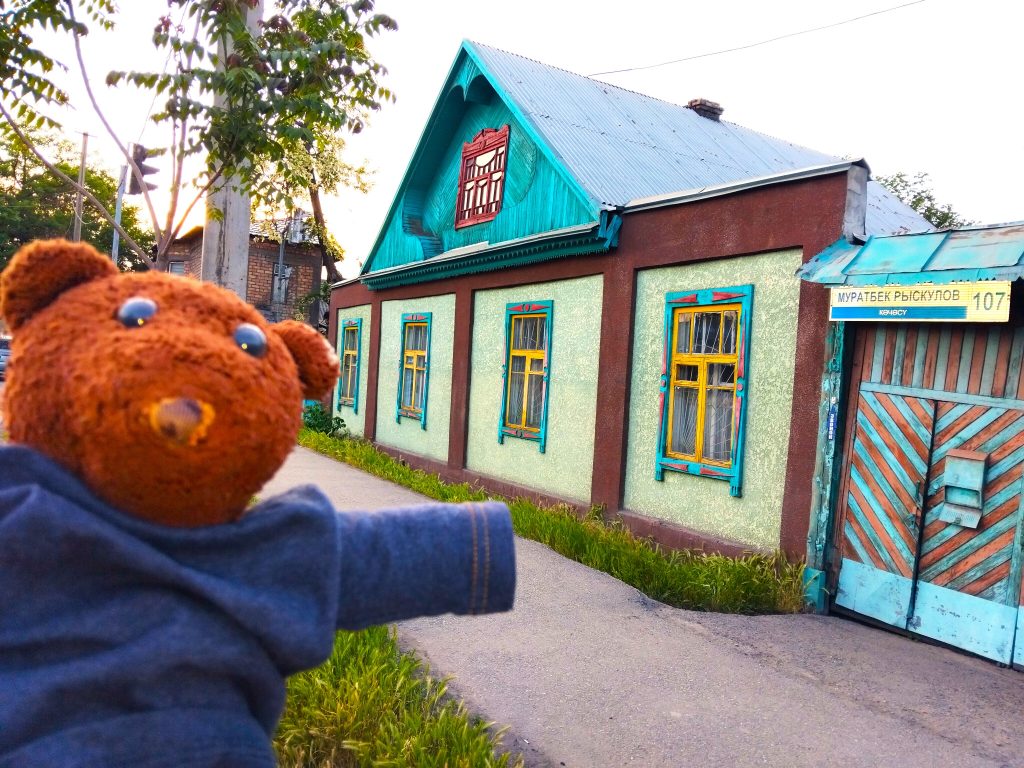 Bearsac the teddy bear in the forerground of a colourful building