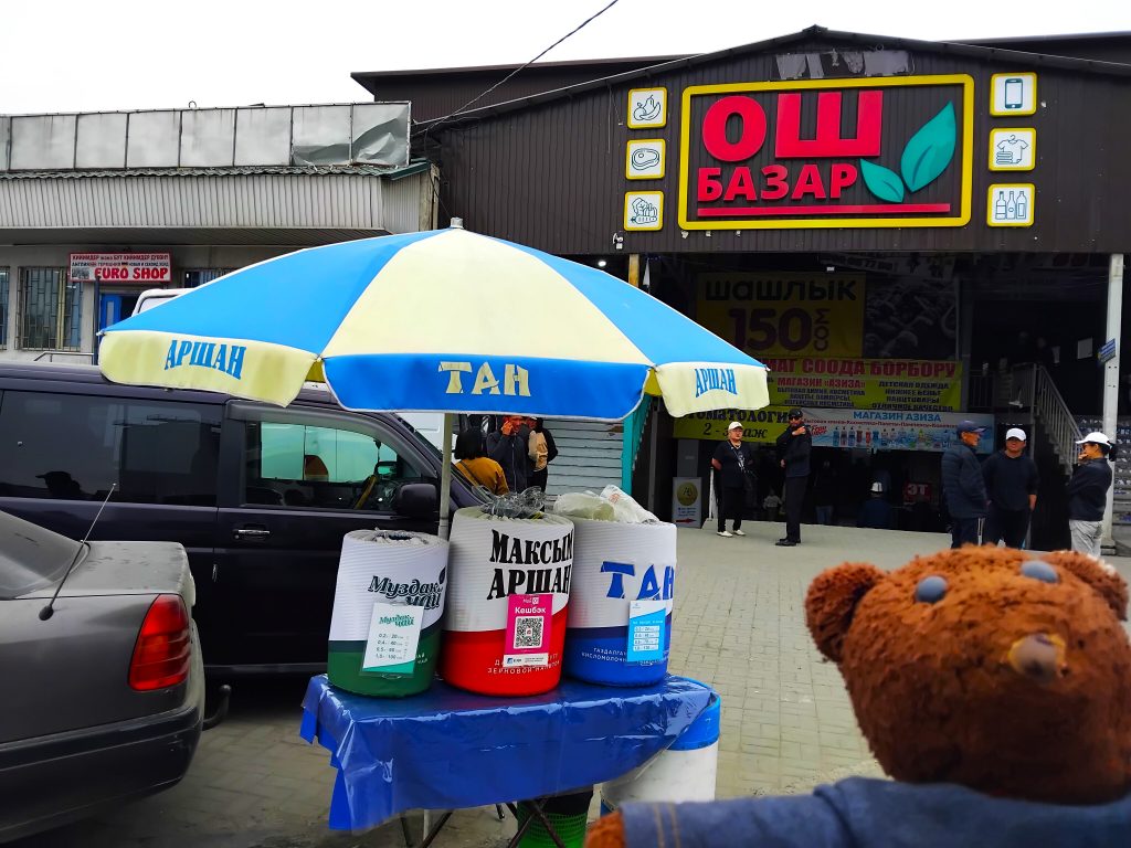 Bearsac the teddy bear in the forerground of barrels of drinks