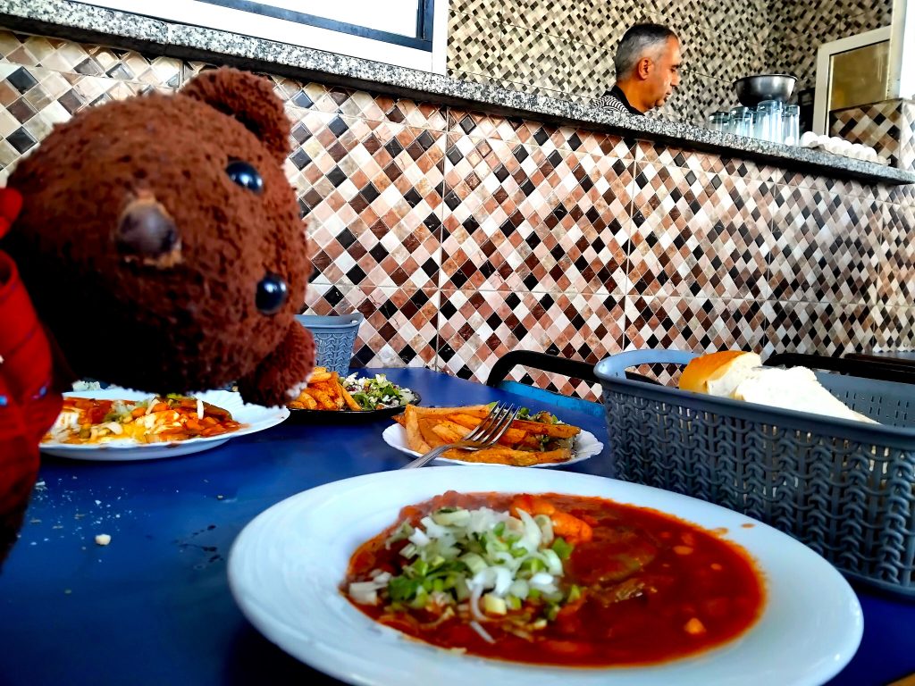 Bearsac the teddy bear peeping into the frame of a bean dish
