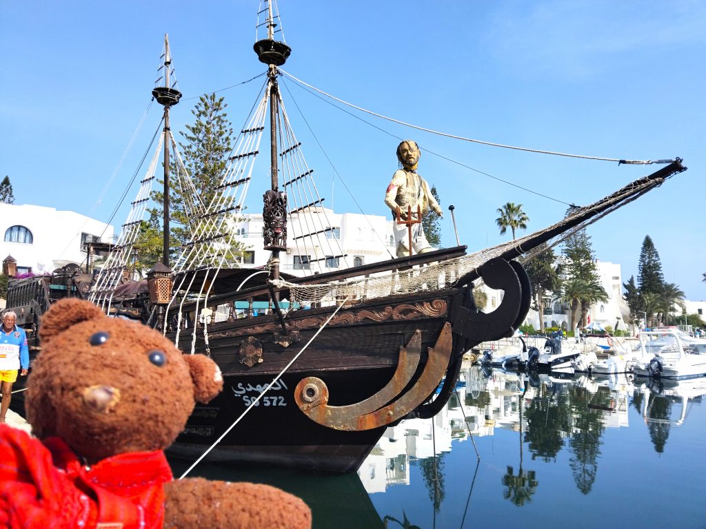 Bearsac the teddy bear in the forground of a pirate style boat