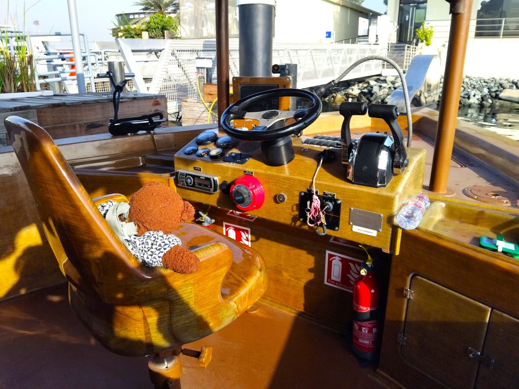 Bearsac the teddy bear sitting in the captains seat on a boat