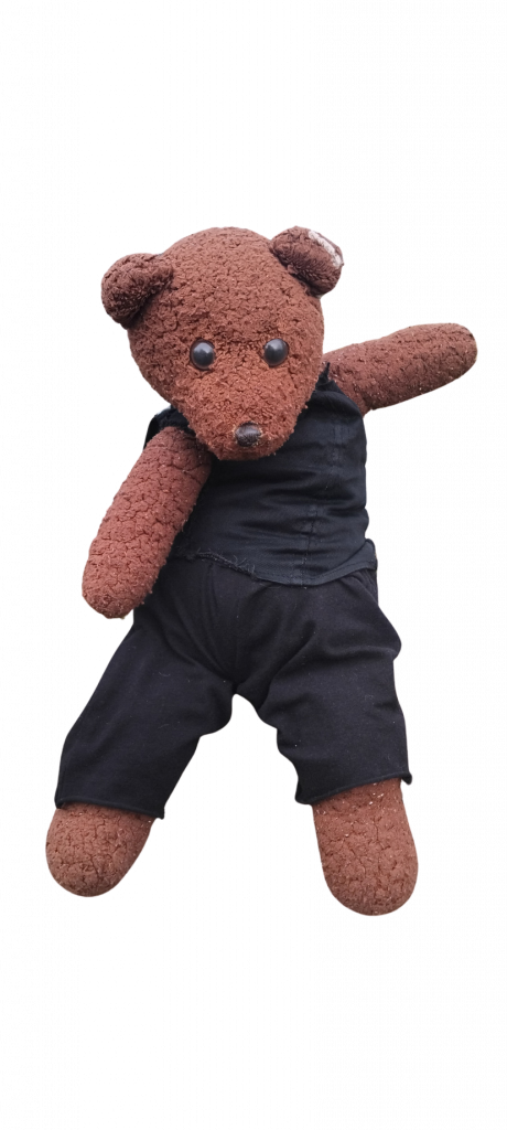 Bearsac the teddy bear wearing blck trousers and vest top.