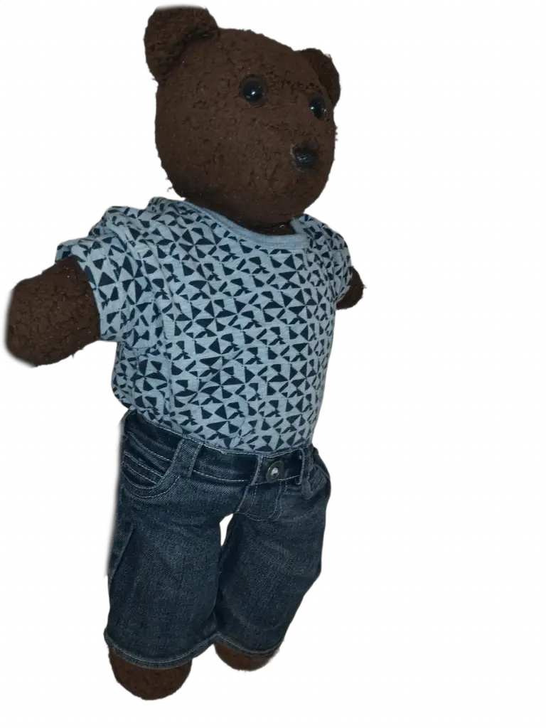 Bearasc the teddy bear wearing blue jeans ans a grey and black top.