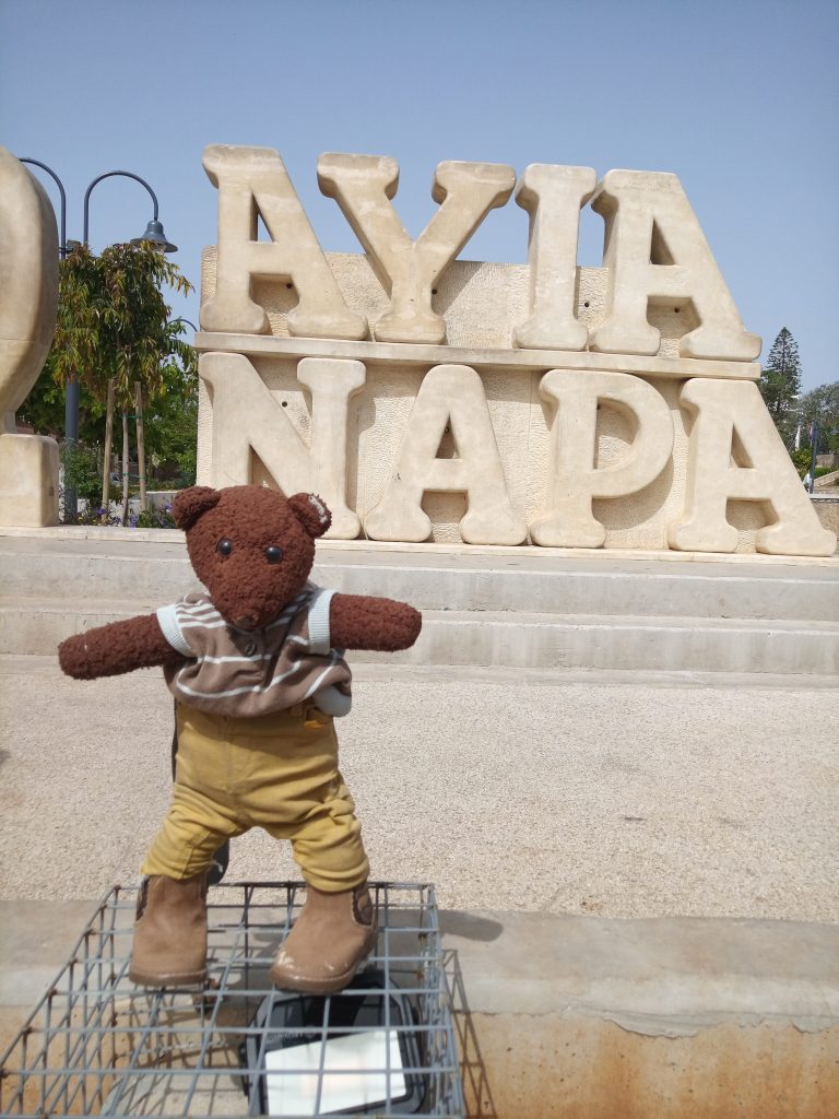 Bearsac the teddy bear in forground of Aiya Napa stone sign.