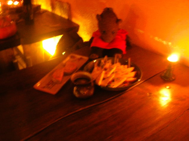 Bearsac sitting ona table with a pltter of cheeses and other food.