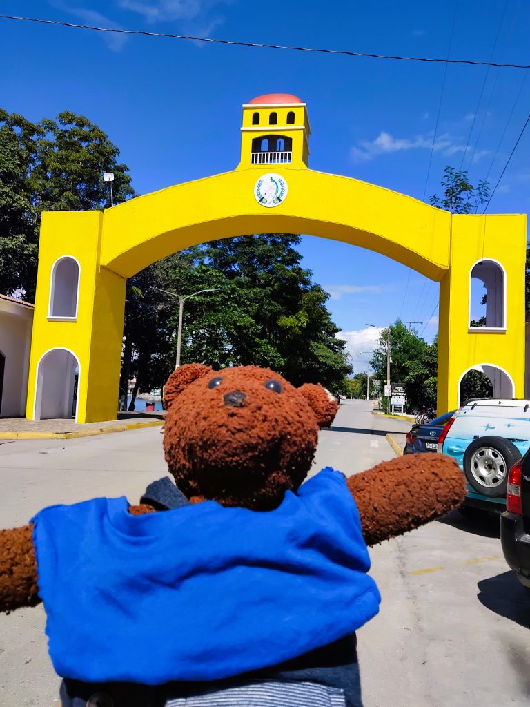 Bearsac the teddy bear in foreground of the yellow gateway to Flores Island