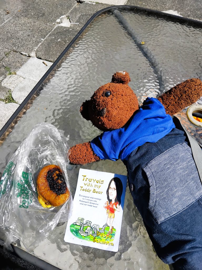 Bearsac the teddy bear lying on a table with a Rellinitos.