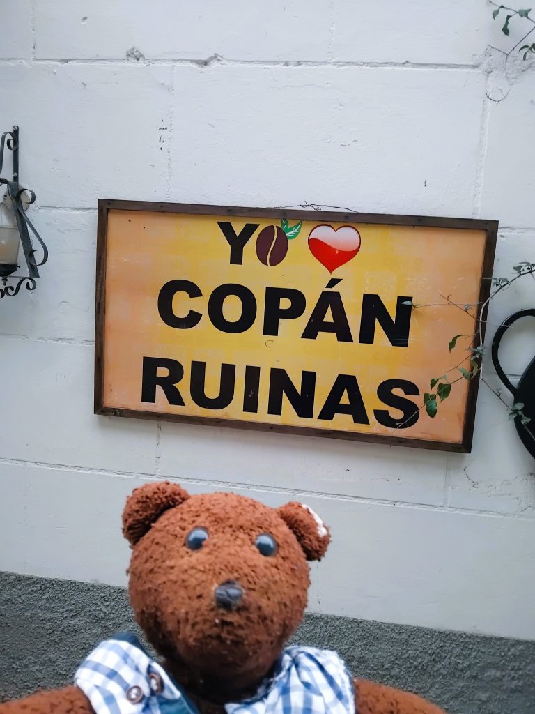Bearsac the teddy bear in foreground of a I Love Copan Ruinas sign.