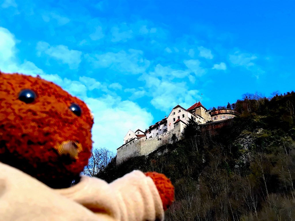Bearsac the teddy bear in forground of Liechtenstein Castle on a hill
