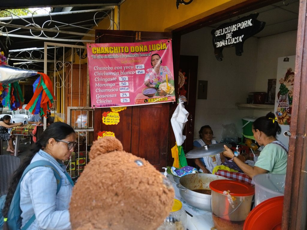 Bearsac the teddy bear in foreground of a street food stand.