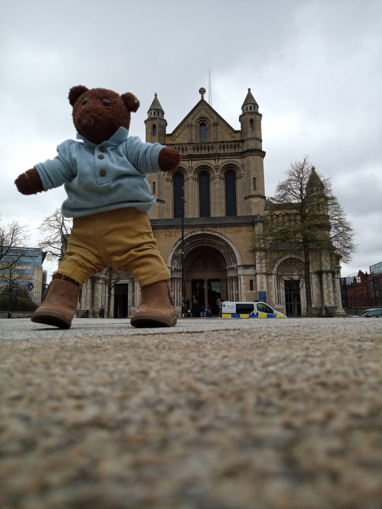 Bearsac the teddy bear in forground of Belfast Cathedral