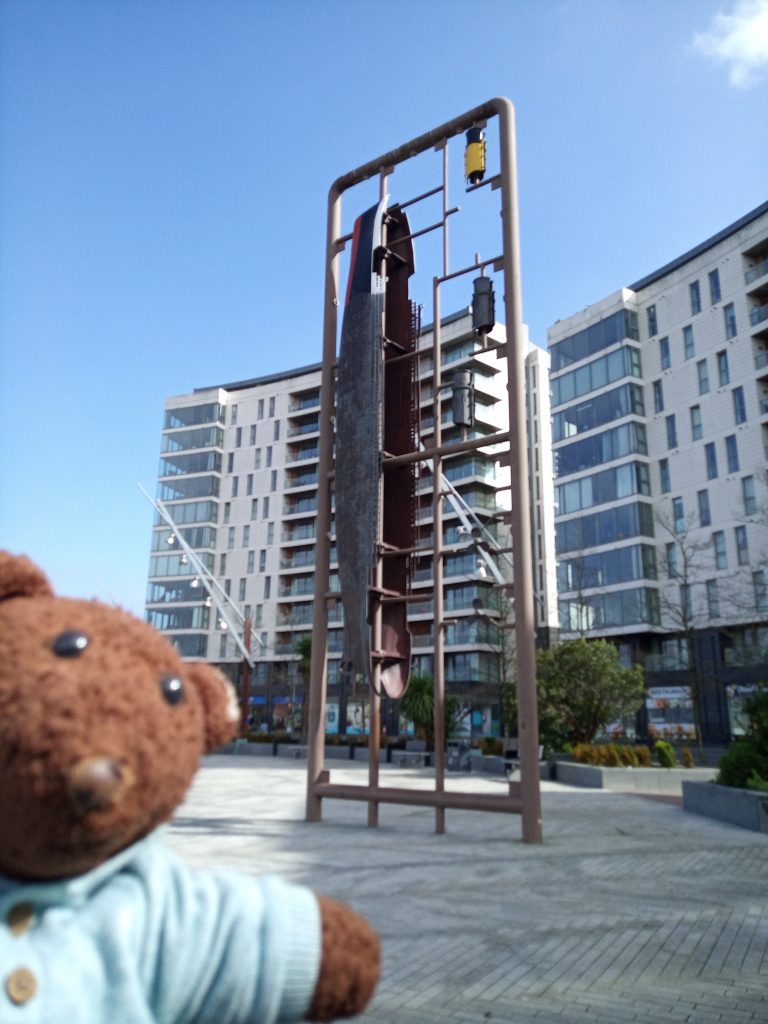 Bearsac the teddy bear in forground of the Titanic Monument
